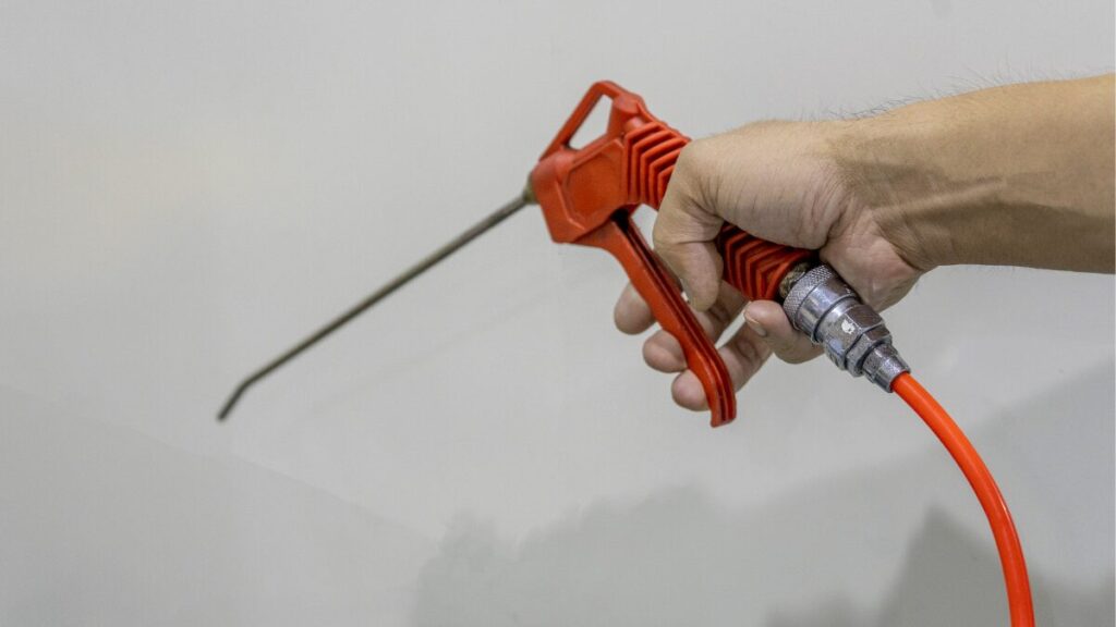 エアーコンプレッサーを動力源にした、エアーダスターガンを手にしている